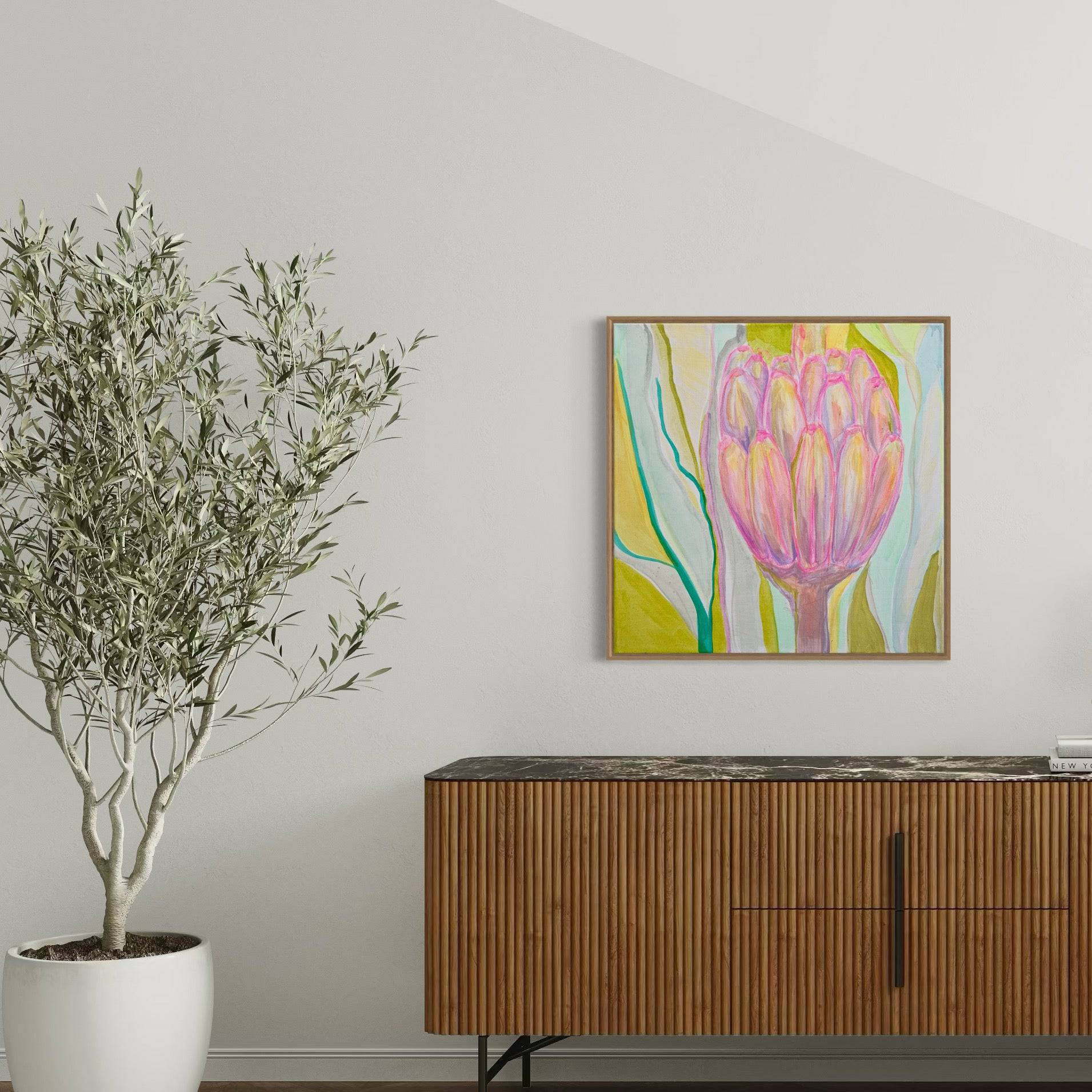 Abstract botanical painting of a pink flower on a white wall above wooden sideboard with black marble top and potted green plant