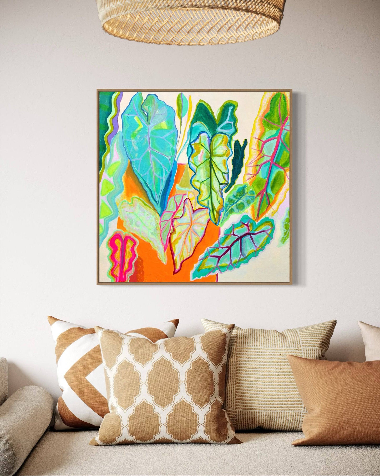 Abstract botanical painting with vibrant green and blue leaves and orange background above beige couch with patterned pillows