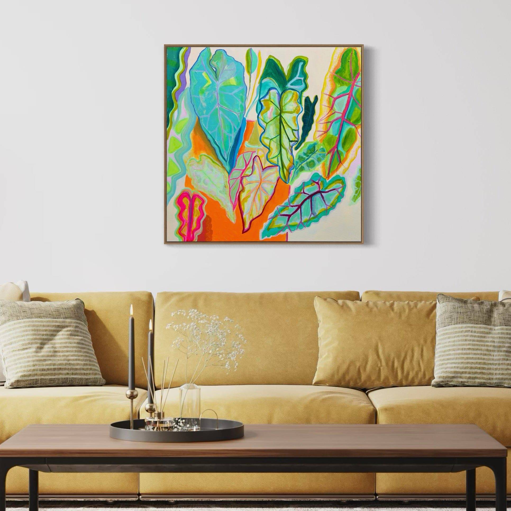 Abstract botanical painting of colorful large leaves by Kathryn Sillince above mustard sofa in modern living room