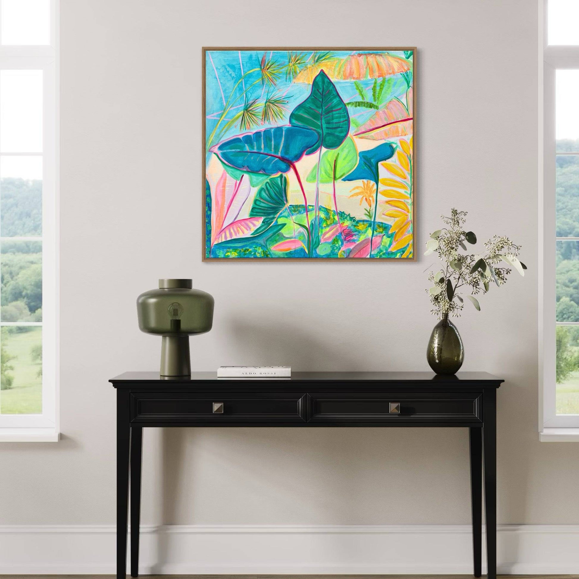 Modern interior with a black console table holding a green lamp, book, and vase, beneath a colorful botanical abstract painting by Kathryn Sillince