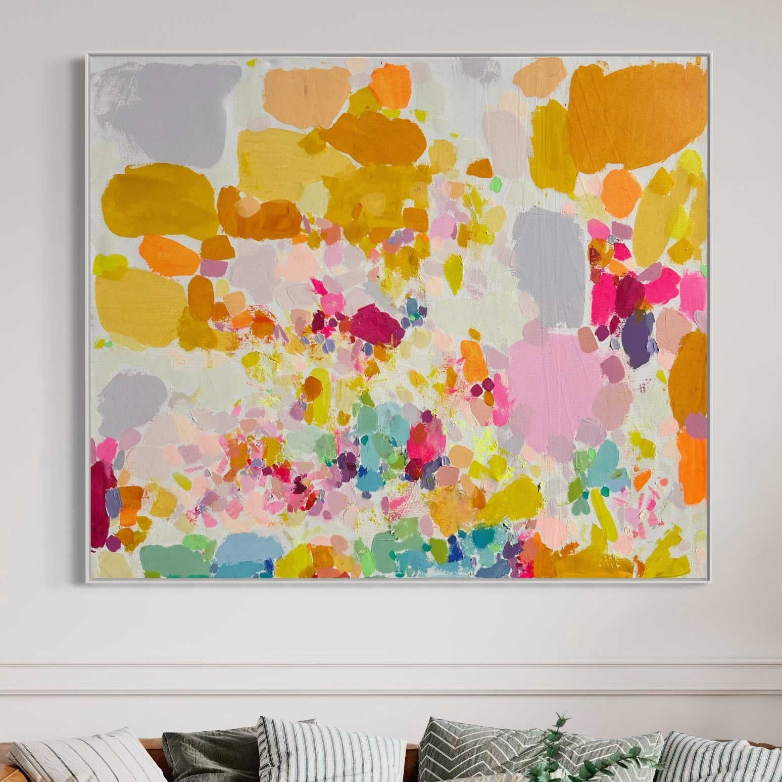 Colorful abstract painting above a sofa with patterned cushions.