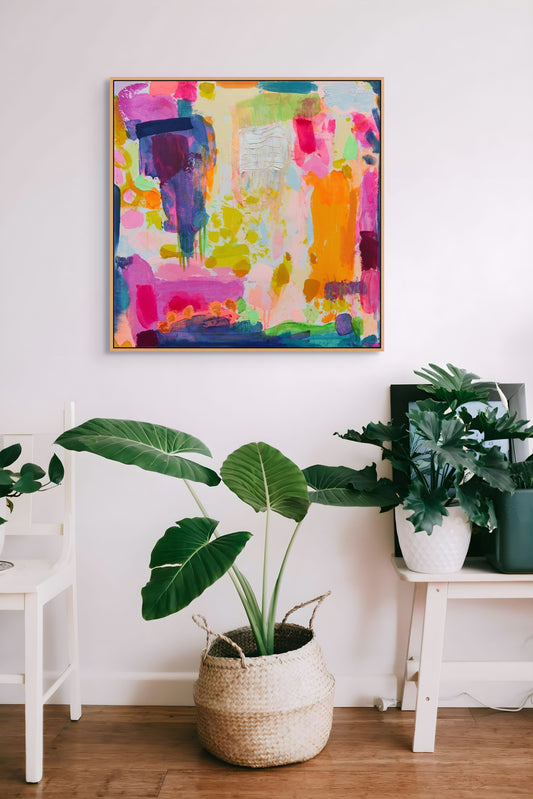 Colorful abstract painting on a wall with plants and furniture in a room.