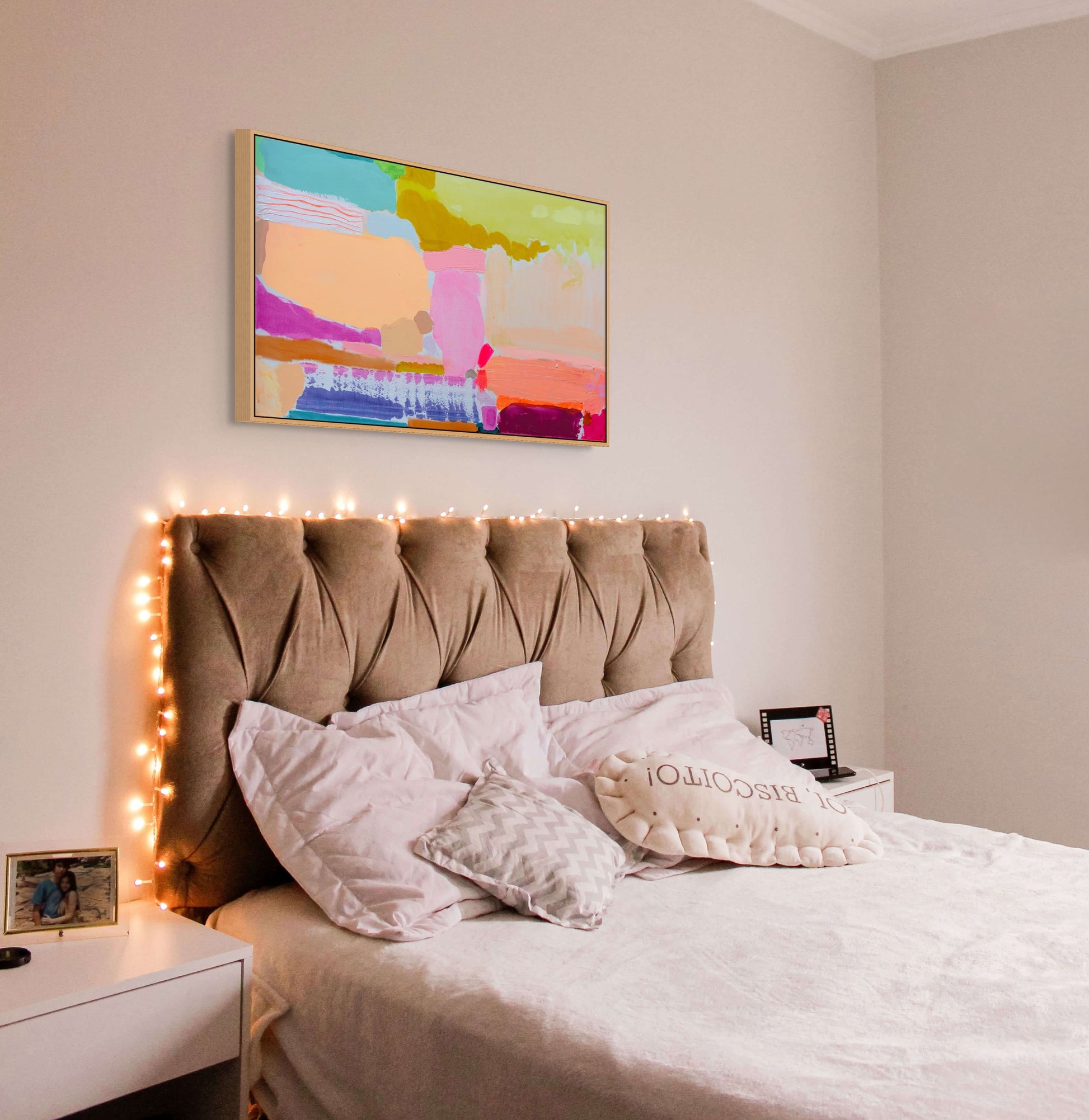 Bedroom with a bed, headboard, and decorative pillows, featuring a colorful abstract painting on the wall.