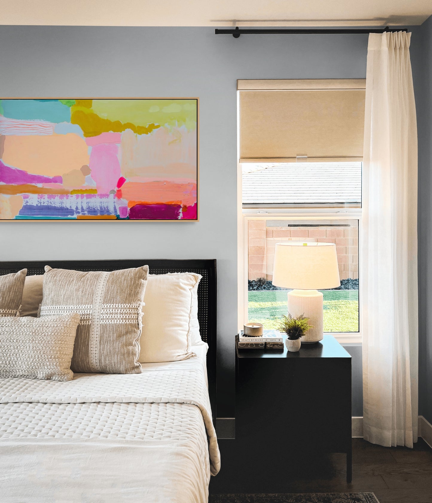Modern bedroom with abstract art, bed, nightstand, and window.