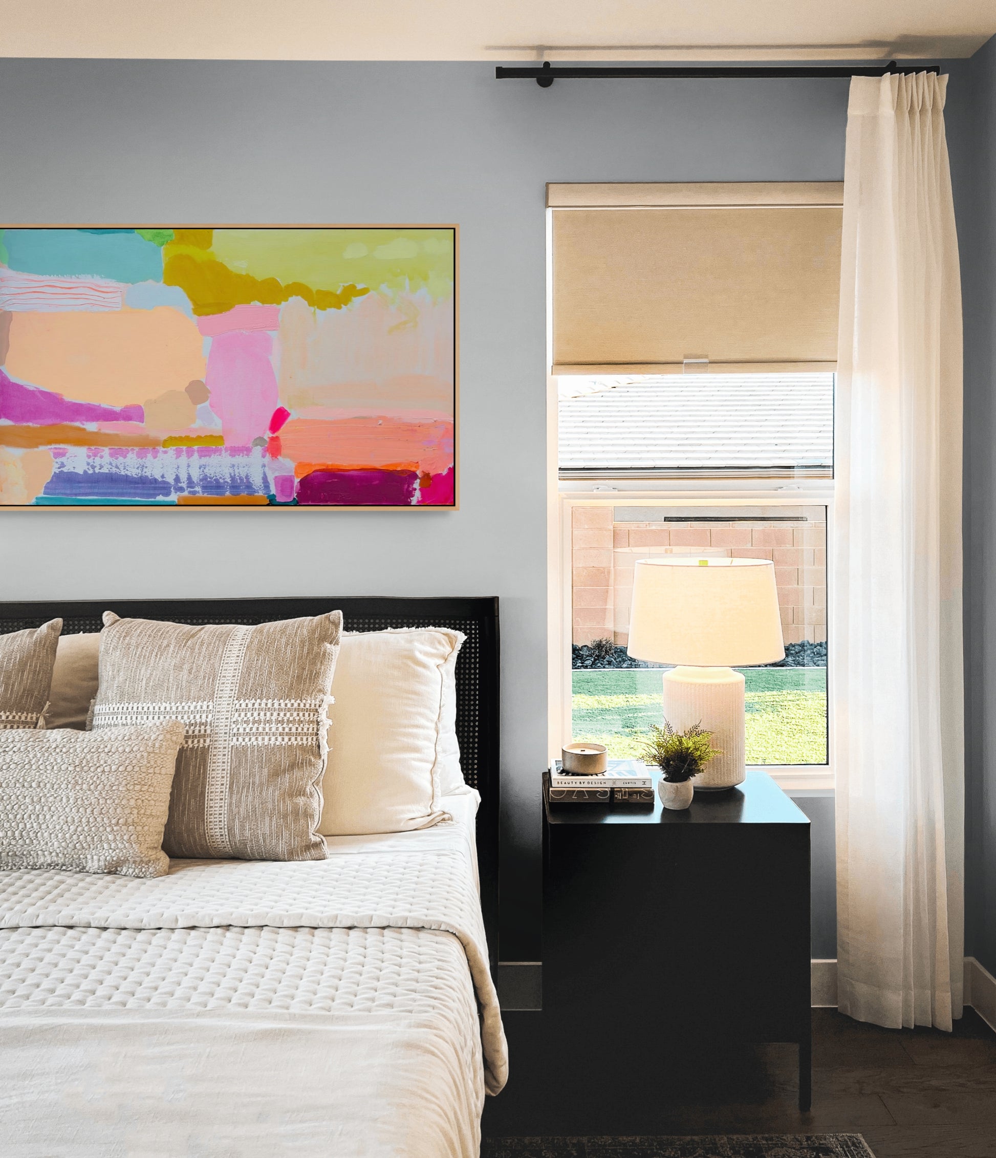 Modern bedroom with abstract art, bed, nightstand, and window.