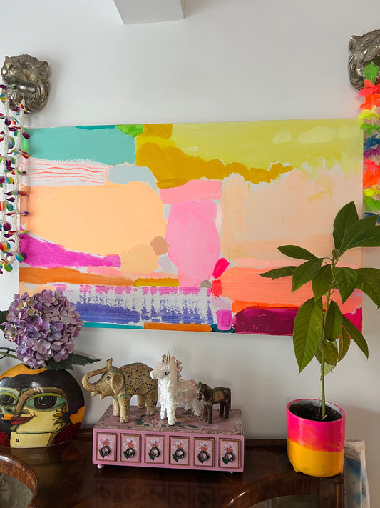 Colorful abstract painting on a wall with decorative items and plants below.